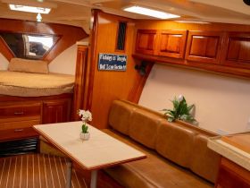 Interior view of a cozy boat cabin featuring a comfortable seating area and dining table, perfect for relaxing during trips on the water.