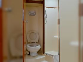 Interior view of a boat bathroom featuring a toilet and shower, designed for convenience while on the water.