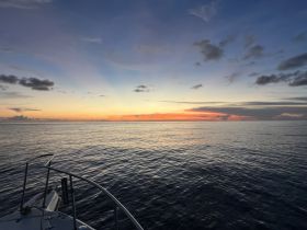 A serene sunset view from the bow of a boat, showcasing tranquil waters and vibrant colors in the sky — perfect for evening cruises.
