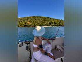 A woman relaxes on a boat, enjoying the scenic views of lush greenery and calm waters, perfect for a tranquil day on the water.