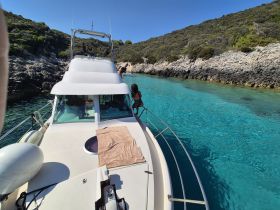 A group enjoys a sunny day on the boat, with one person preparing to jump into the crystal-clear waters — a perfect setting for summer adventures.
