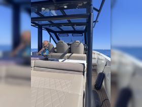 A young boy enjoys the spacious interior of a modern boat, featuring comfortable seating and a sleek helm design, perfect for family outings on the water.