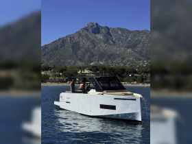 A sleek boat glides through clear waters with stunning mountain scenery in the background, capturing the essence of a perfect day on the water.