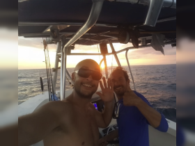Two friends enjoy a sunset on the water, capturing a joyful moment aboard their fishing boat — perfect for memorable adventures at sea.