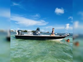 A woman enjoys the sun on a boat while a child plays in the water, capturing a perfect family day out on the beach.