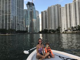 A mother and her child enjoy a relaxing moment on a boat, surrounded by stunning city skyscrapers — a perfect family outing on the water.