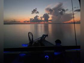 A serene sunset view from a boat, with a hint of fishing gear visible, creating a perfect backdrop for evening adventures on the water.