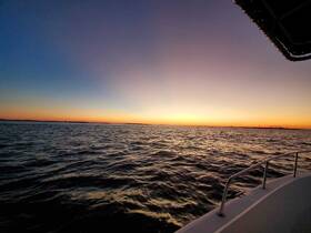 A serene sunset view over the water, captured from the deck of a boat, showcasing the tranquil beauty of evening cruises.