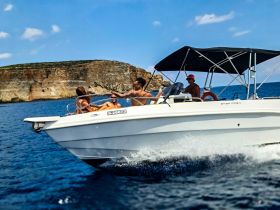 A lively group enjoys a day on the water aboard a speedboat, showcasing the fun of boating adventures against a stunning coastal backdrop.