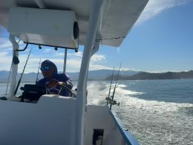 A skilled captain navigates a fishing boat through calm waters, showcasing the thrill of on-water adventures and fishing experiences.