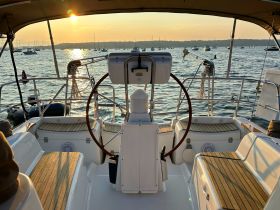 A serene view of the helm area inside a boat, showcasing the console and seating as the sun sets over the water, perfect for a relaxing day on the sea.