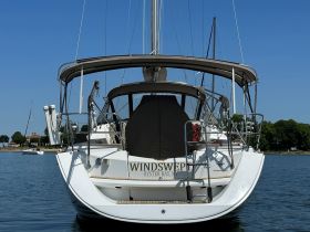 A stunning view of the 'Windswept' yacht docked peacefully, showcasing its elegant design against a clear blue sky — perfect for luxury sailing experiences.