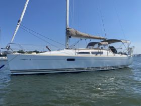 A sleek sailboat docked in calm waters, showcasing its elegant design against a clear blue sky — perfect for sailing enthusiasts and charters.