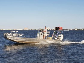 A man navigates a speedboat through calm waters, showcasing the thrill of boating adventures.