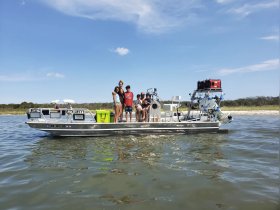 A joyful group of family members enjoys a day on the water aboard a boat, capturing the essence of summer fun and adventure.