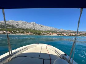 A scenic view from the bow of a boat, showcasing the stunning coastline and mountainous backdrop — perfect for exploring the beautiful waters.