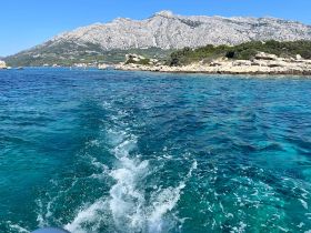 A stunning view of turquoise waters and a rocky coastline, showcasing the natural beauty of the area — perfect for exploring by boat.