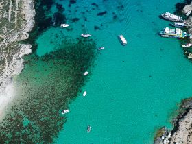 A stunning aerial view of boats anchored in crystal-clear turquoise waters, showcasing the beautiful coastline and vibrant marine life — perfect for a day of exploration and relaxation.
