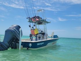 A sleek Ranger boat equipped with fishing gear, anchored in clear turquoise waters, perfect for a day of fishing adventures.