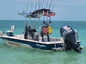 A sleek Ranger speedboat named 'About Time' is anchored in clear turquoise waters, showcasing its fishing gear and inviting design — perfect for a day on the water.
