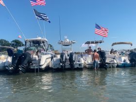 A lively group enjoys a day on the water, surrounded by boats and American flags, creating the perfect atmosphere for summer fun and celebration.