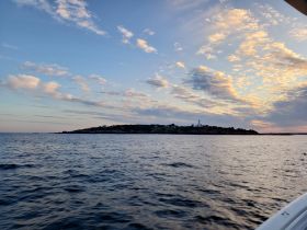 A picturesque sunset view of an island coastline, showcasing the tranquil beauty of the water and sky — perfect for scenic boat trips.