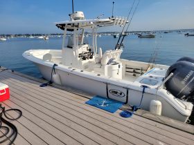 A pristine center console boat docked at the marina, showcasing its sleek design and fishing gear — perfect for a day out on the water.