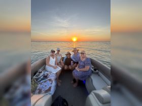 A group of friends enjoys a picturesque sunset aboard a pontoon boat, creating unforgettable memories on the water.