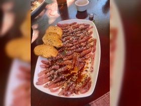 A beautifully arranged platter of sliced fish with sesame seeds and toast, perfect for onboard dining experiences or catering during boat trips.