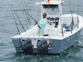 A fisherman poses with his catch aboard a fishing boat, showcasing the excitement of a day on the water.
