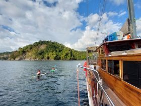 Two kayakers paddle alongside a beautiful island backdrop, showcasing a serene day on the water — perfect for adventure seekers and nature lovers.