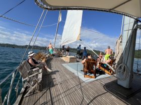 A lively group enjoys a sailing experience on a beautiful day, showcasing the joy of being on the water with friends.