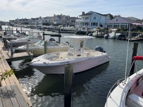 A beautiful view of a boat docked at a marina, showcasing the vessel's sleek design against a backdrop of waterfront homes.