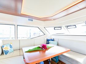 A beautifully designed interior of a boat featuring comfortable seating and a table adorned with tropical flowers, perfect for relaxing and enjoying the view.