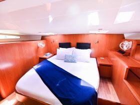 A cozy cabin interior featuring a comfortable bed and warm wooden finishes, perfect for relaxing on a boat getaway.