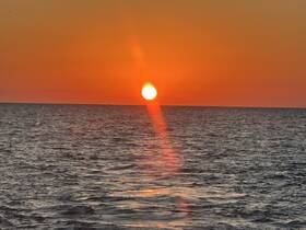 A stunning sunset over the ocean, casting vibrant colors across the sky and water — a perfect backdrop for evening boat cruises.