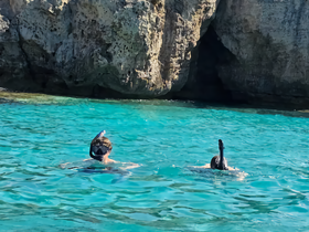 Two snorkelers explore the vibrant underwater world in crystal-clear waters, surrounded by stunning rock formations — a perfect adventure for marine enthusiasts.