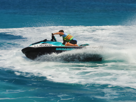 A thrilling moment captured as a rider maneuvers a jet ski through the waves, showcasing the excitement of water sports in a beautiful ocean setting.