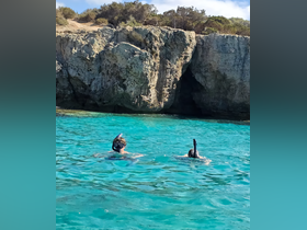 Two snorkelers explore the vibrant turquoise waters near a stunning rock formation, showcasing the beauty of underwater adventures.