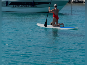 A woman paddleboards with a child in the clear blue waters, showcasing a fun family activity perfect for summer adventures.