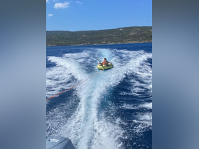 A child enjoys tubing on a bright summer day, being towed behind a boat through sparkling blue waters — a thrilling water activity perfect for family fun.