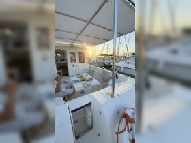 A cozy dining setup inside a boat, featuring a table laid with food and drinks, as the sun sets in the background — perfect for intimate gatherings or sunset dinners on the water.