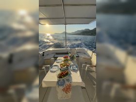 A beautifully arranged dining table on a boat featuring fresh fruits and drinks, perfect for enjoying a meal while cruising along scenic coastlines.