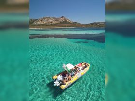 A lively group enjoys a day on a boat in crystal-clear turquoise waters, perfect for island hopping and summer adventures.