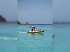 A lively group enjoys a ride on a yellow boat through crystal-clear turquoise waters, perfect for summer adventures and exploring coastal destinations.