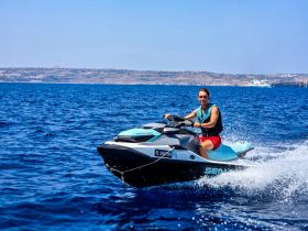 A joyful rider enjoys a thrilling jet ski adventure on crystal-clear waters, showcasing the excitement of water sports.