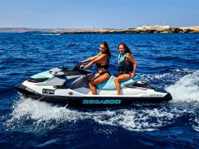Two friends enjoy a thrilling ride on a jet ski, capturing the excitement of on-water activities in a beautiful coastal setting.