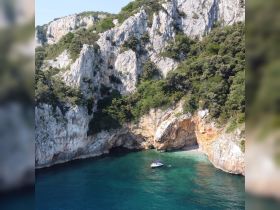 A stunning aerial view of a boat anchored near a secluded beach, surrounded by dramatic cliffs and crystal-clear waters, perfect for exploring hidden gems along the coastline.