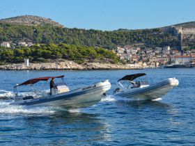 Two speedboats navigate the clear waters, showcasing the stunning coastal scenery and vibrant town in the background — perfect for exploring the beautiful coastline.