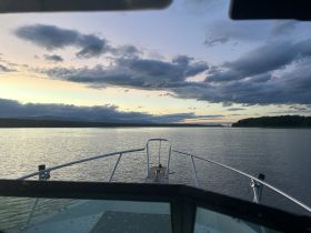 A serene view from the front of a boat, showcasing calm waters and a picturesque sunset sky, perfect for peaceful cruising or fishing trips.